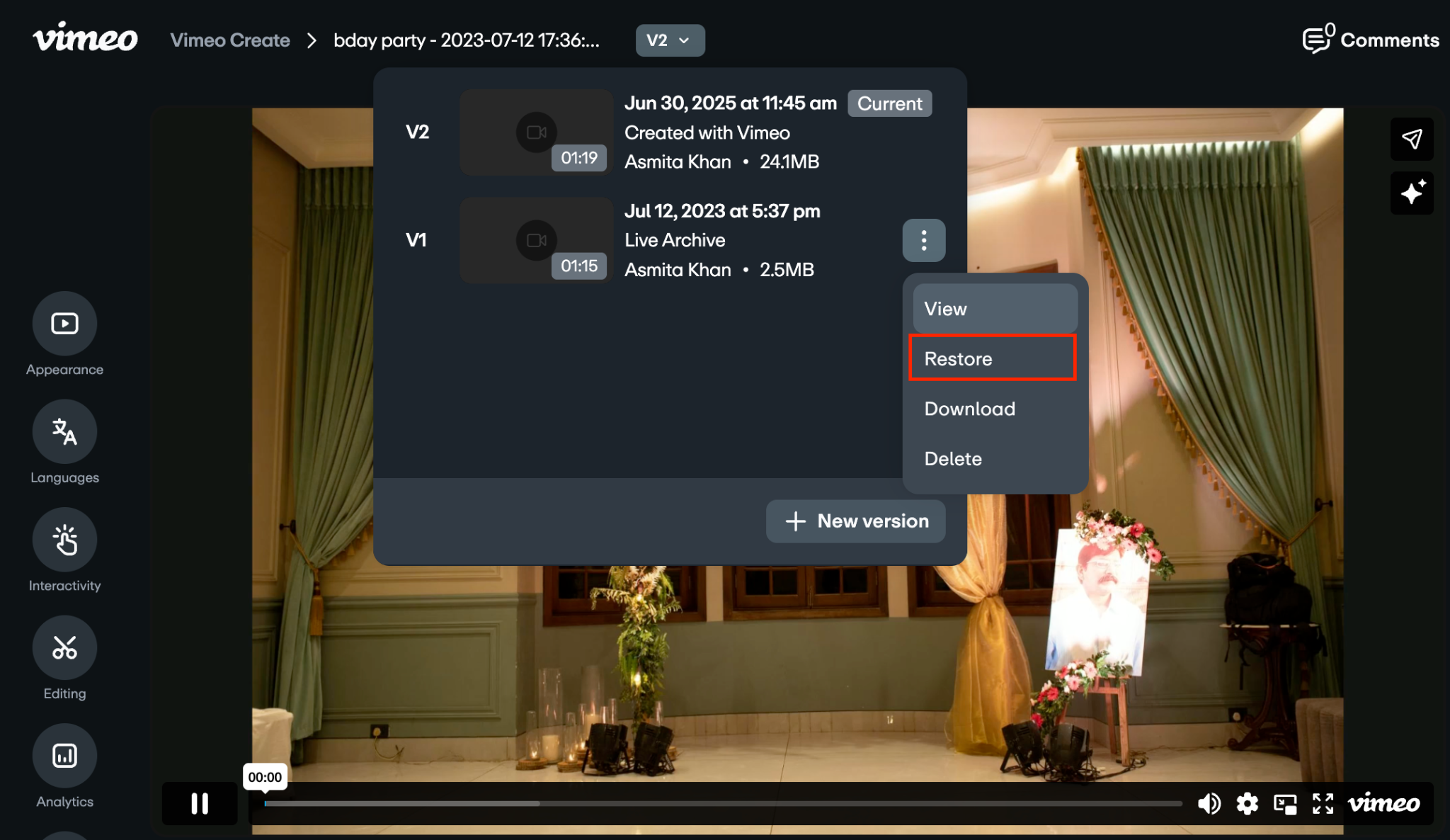 Video player screen showing the version history popup. The three-dot menu next to V1 is open, displaying 'View,' 'Restore,' 'Download,' and 'Delete' options, with 'Restore' highlighted.